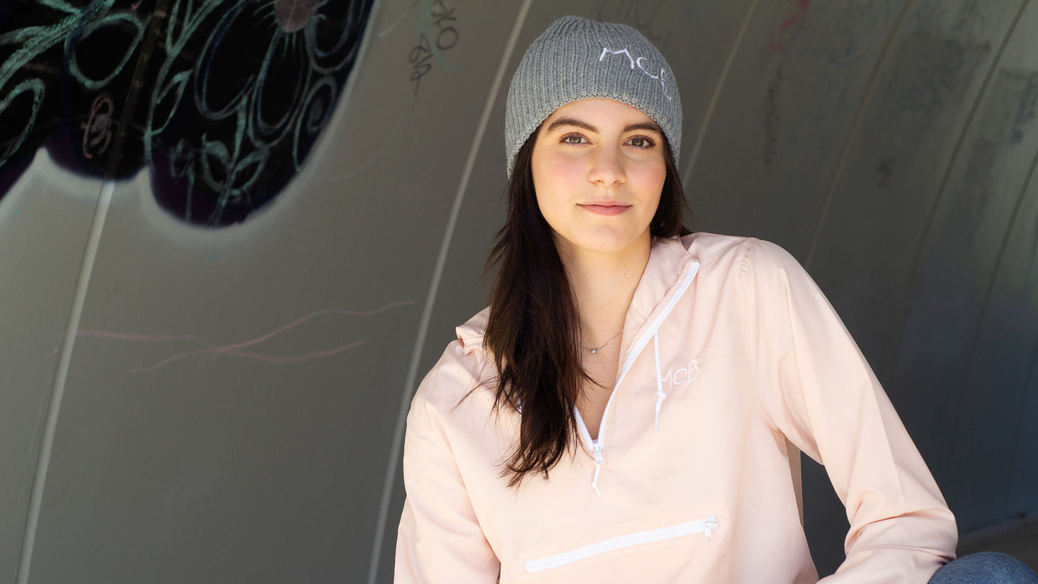 Girl posing in windbreaker and beanie.